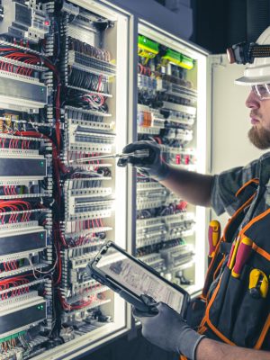 Electrician focused on work in switchboard with fuses, using tablet. Young adult electrical engineer in special clothes with flashlight on helmet in dark room with emergency lights in background. SSUCv3H4sIAAAAAAAAA41Py46DMAz8F5+DxKtd4FeqPYTEhaiBVImzVYXy7+sA1V43J3vGmccGRsMAWl51W+uyUNi3RVXhvRj7Uhbqq22xazp1VRoEnxHCUDVNV9VNXV7qS1+V/ASMMhgFwwbG2hjISzJuhYEZj6tGv4+oDTlvpOUtCQgkKQYM/I03xdoTs/v+0bttGeeAbB7imIck/ol9C5ATruqd9VMOYlHudjemHi9Cv5zejuYckUVcXMm/DyHr3FOOlhvfpQ0oYJYh8IE+Af749EaZdTobcHG3HPPqKDvteciph9Gn1VF6Noxmnw3i0zqpUZ90HBdD9Fk9/hh8/V2nlH4Bu48wSbIBAAA=