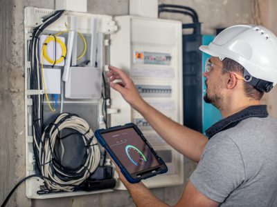 Man, an electrical technician working in a switchboard with fuses. Installation and connection of electrical equipment.